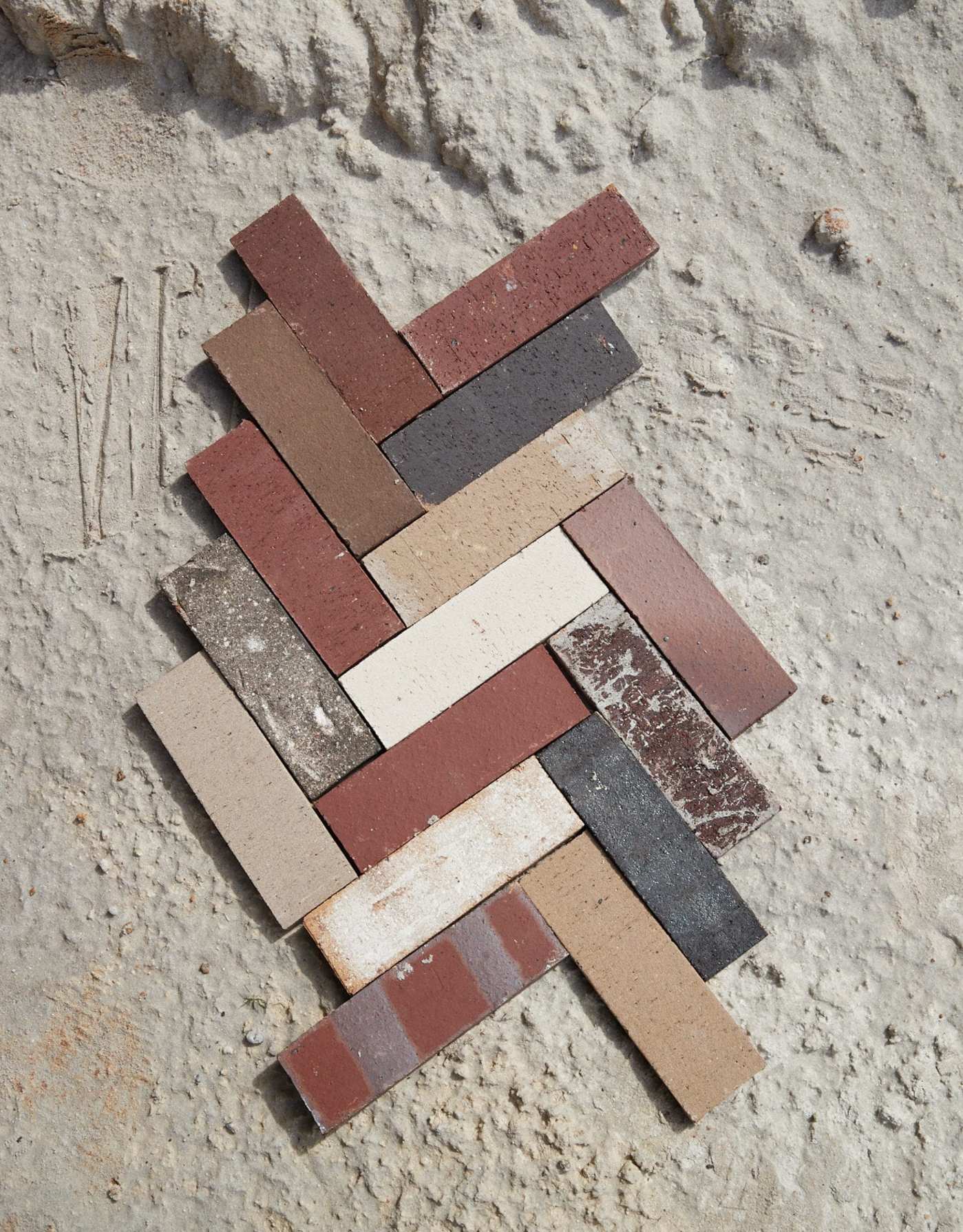 a group of various colored bricks arranged in a pattern on a sandy surface.