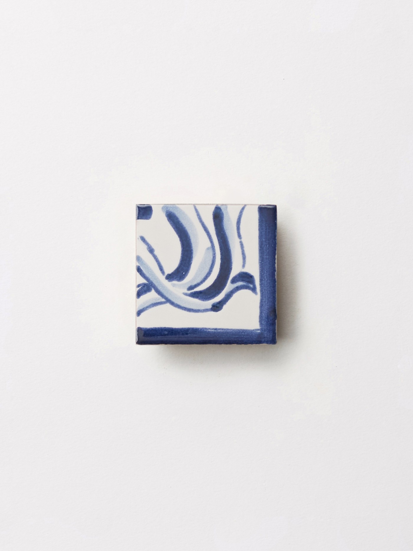 a blue and white hand painted tile on a white surface.