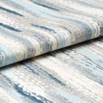Low-pile woven rug with blue, gray, and cream abstract streaks; folded over itself; tight close-up studio view emphasizing woven texture and layered edges.