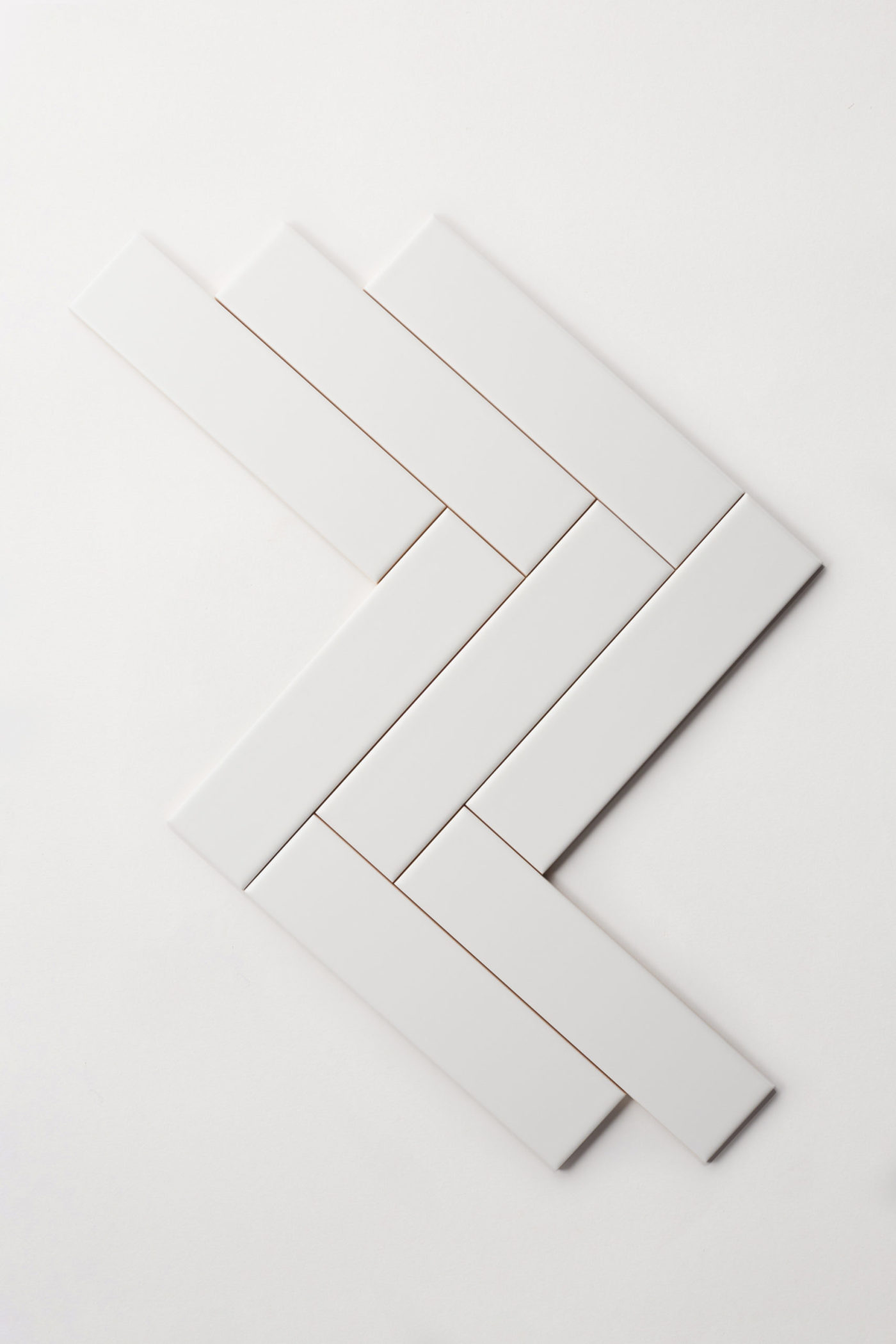 a set of white tiles in a herringbone pattern on a white background.