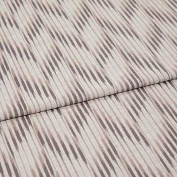 Folded patterned fabric with diagonal ikat-style stripes in muted taupe and blush lies folded across the frame, showing woven texture and subtle vertical lines in a studio-lit close-up.