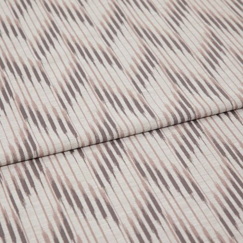 Folded patterned fabric with diagonal ikat-style stripes in muted taupe and blush lies folded across the frame, showing woven texture and subtle vertical lines in a studio-lit close-up.