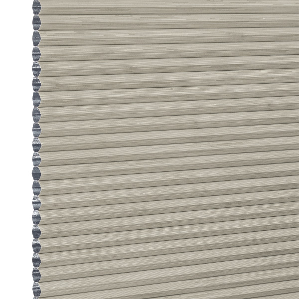 Beige honeycomb cellular window blind with pleated horizontal ribs and exposed left-edge cells — fully lowered and closed, blocking view; close-up fills frame in neutral, even lighting.