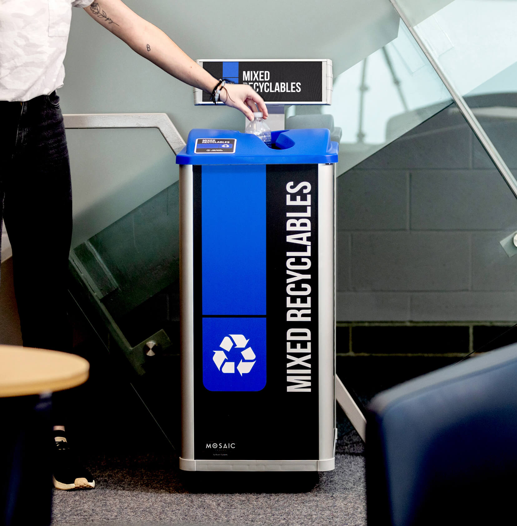 mixed recyclables bin in a college campus with body signs and showing a person depositing a plastic bottle inside