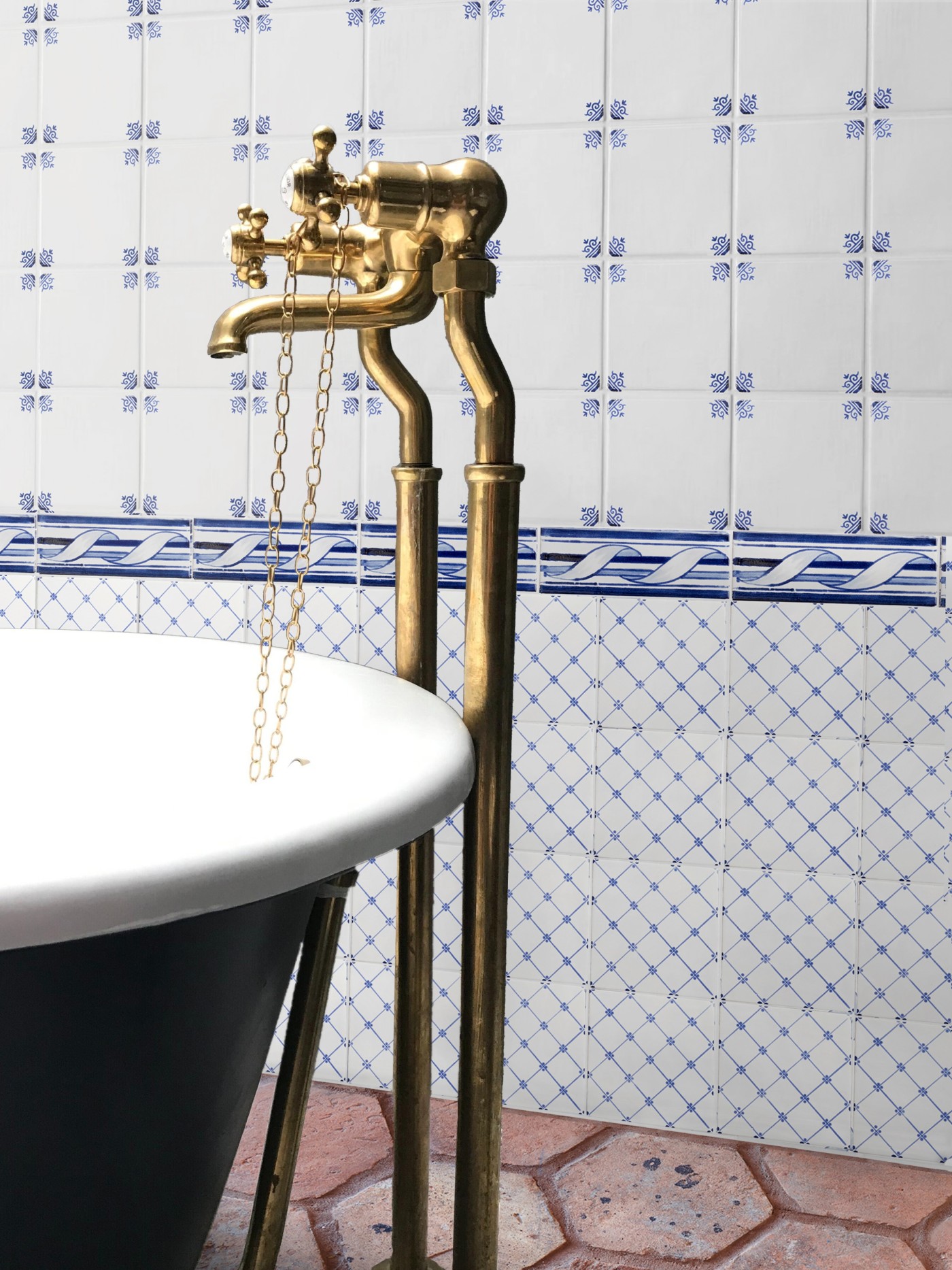 a bathtub with a brass faucet and tiled floor and wall.