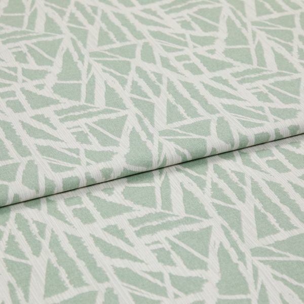 Folded pale green-and-white woven fabric with angular, leaf-like geometric pattern and subtle ribbed texture â€” overlapped across the frame â€” close-up on a flat, softly lit studio background.