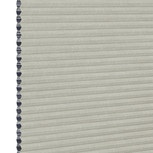 A closed light-gray cellular (honeycomb) window shade, hexagonal dark-gray cell edges visible along the left; filtering light while covering the opening; close-up view with neutral, even lighting.