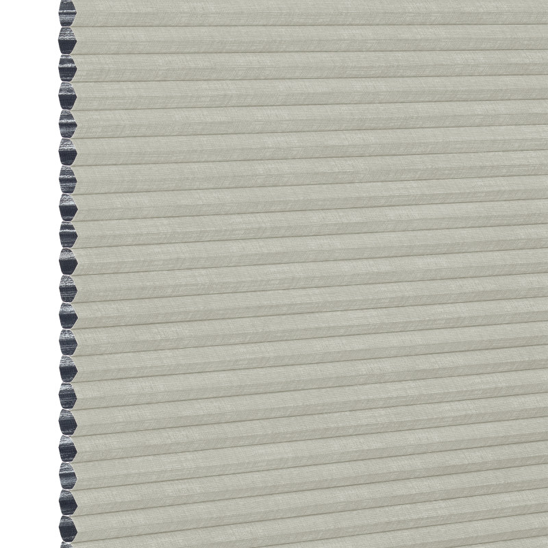 A closed light-gray cellular (honeycomb) window shade, hexagonal dark-gray cell edges visible along the left; filtering light while covering the opening; close-up view with neutral, even lighting.