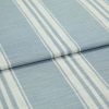 Blue-and-white striped woven fabric (curtain sample) folded into layers; vertical white stripe bands on pale blue ground, textured weave visible, close-up on flat surface under soft, even lighting.