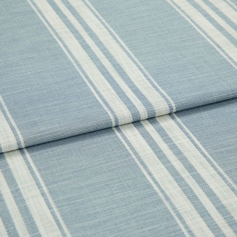 Blue-and-white striped woven fabric (curtain sample) folded into layers; vertical white stripe bands on pale blue ground, textured weave visible, close-up on flat surface under soft, even lighting.