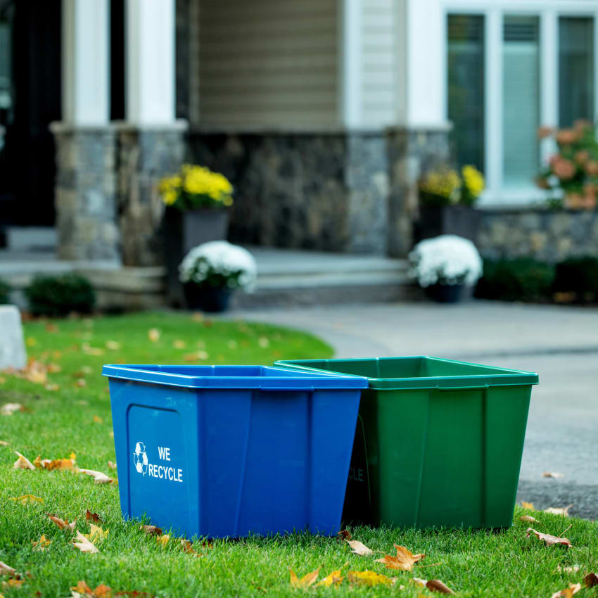 large capacity durable blue and green recycling and organics bins sitting on a residential property
