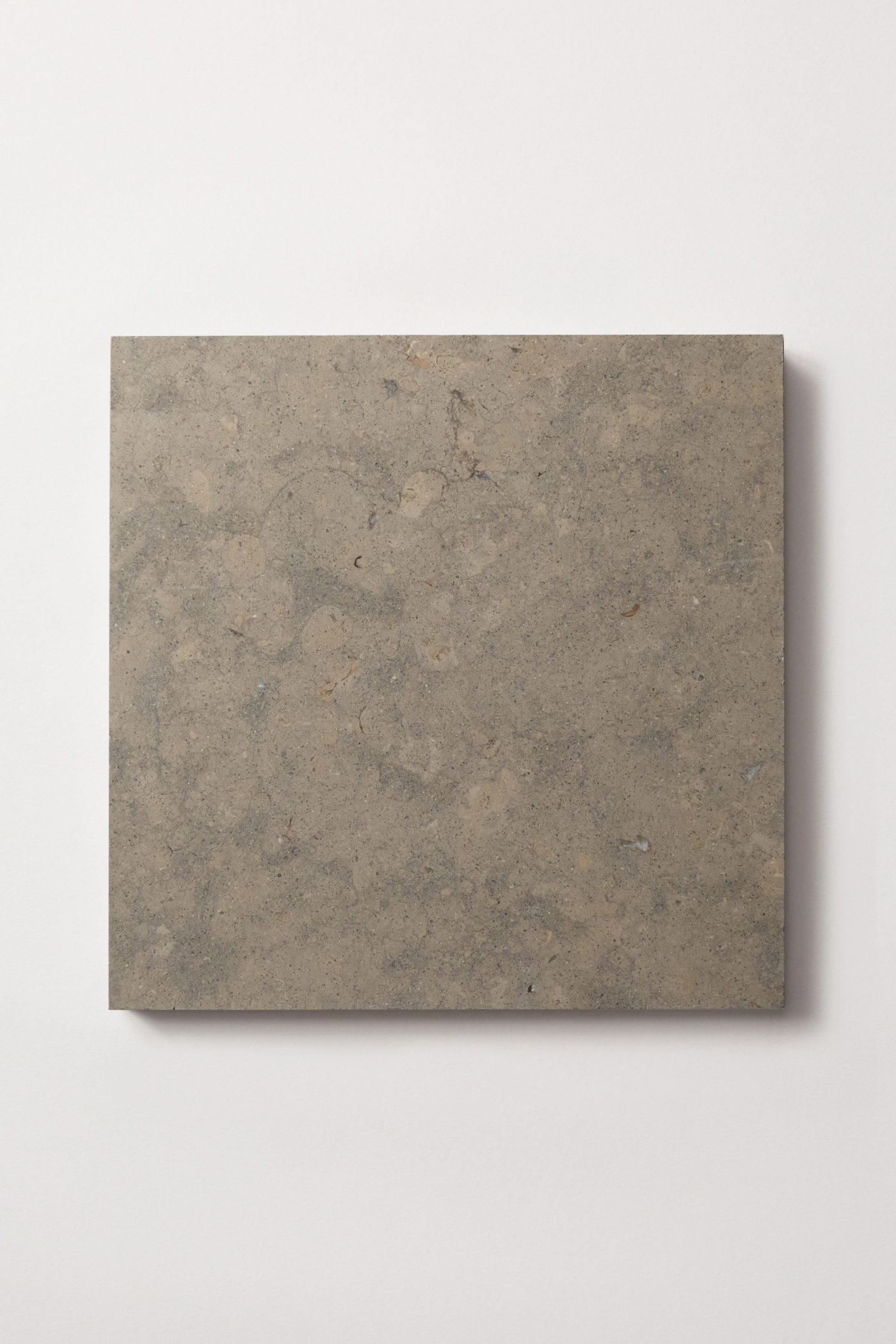 a piece of square grey limestone on a white surface.