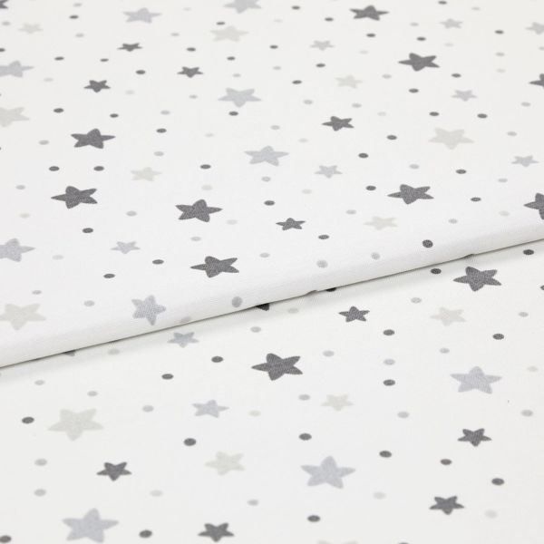 White cotton fabric patterned with scattered grey stars and small dots, folded and layered on itself; photographed as an evenly lit close-up, resembling a nursery textile sample.