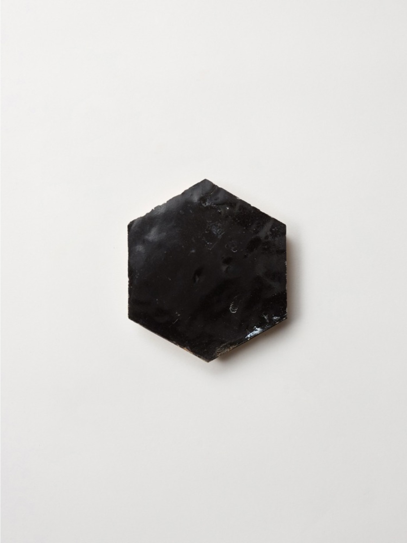 a black hexagonal tile on a white surface.