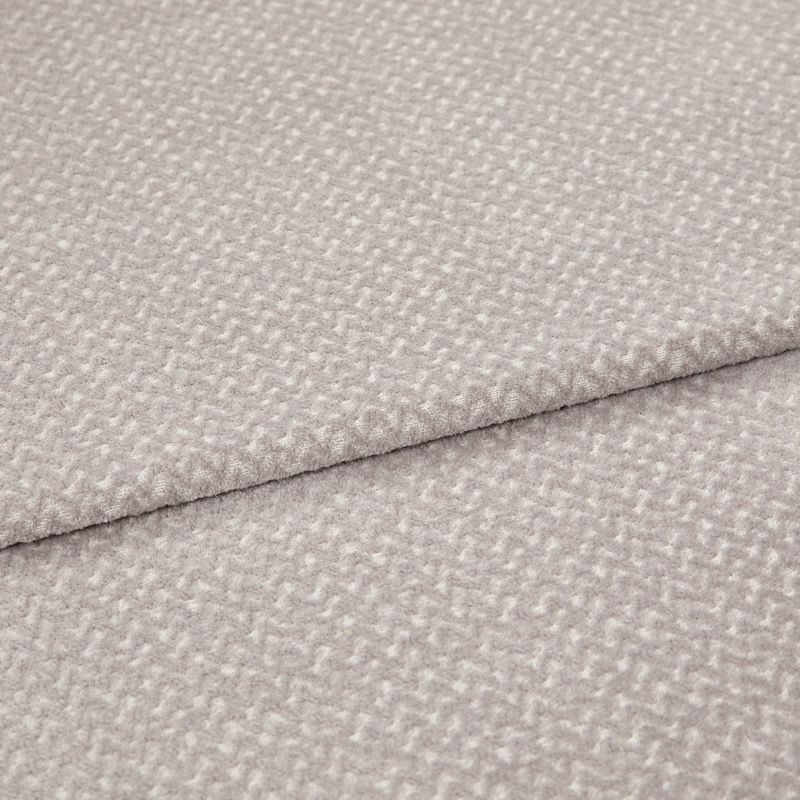 Light gray textured fabric with a small raised pebble pattern, layered in two overlapping folds; fabric lies flat with a slightly raised seam; close-up studio shot with soft, even lighting.