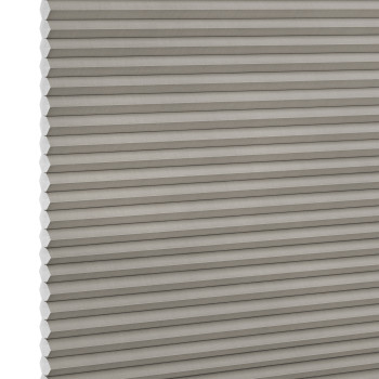 Grey honeycomb (cellular) blind, fully lowered with visible hexagonal cells along the left edge, blocking light; close-up product shot with even lighting and white background.