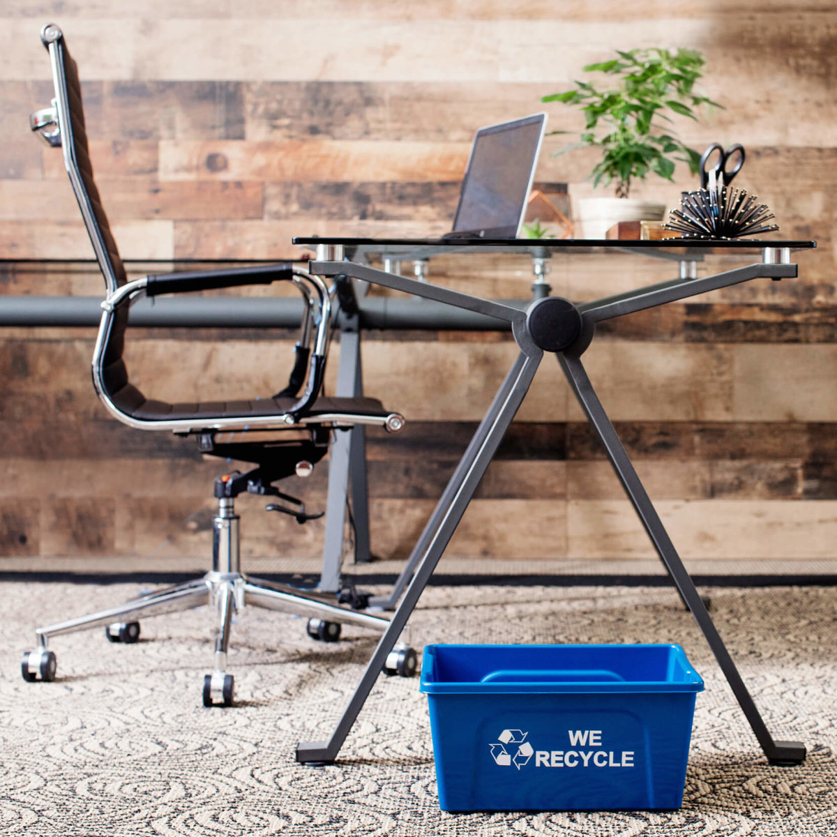 blue deskside recycling bin with we recycle stamped on the side sitting on the floor in a modern office