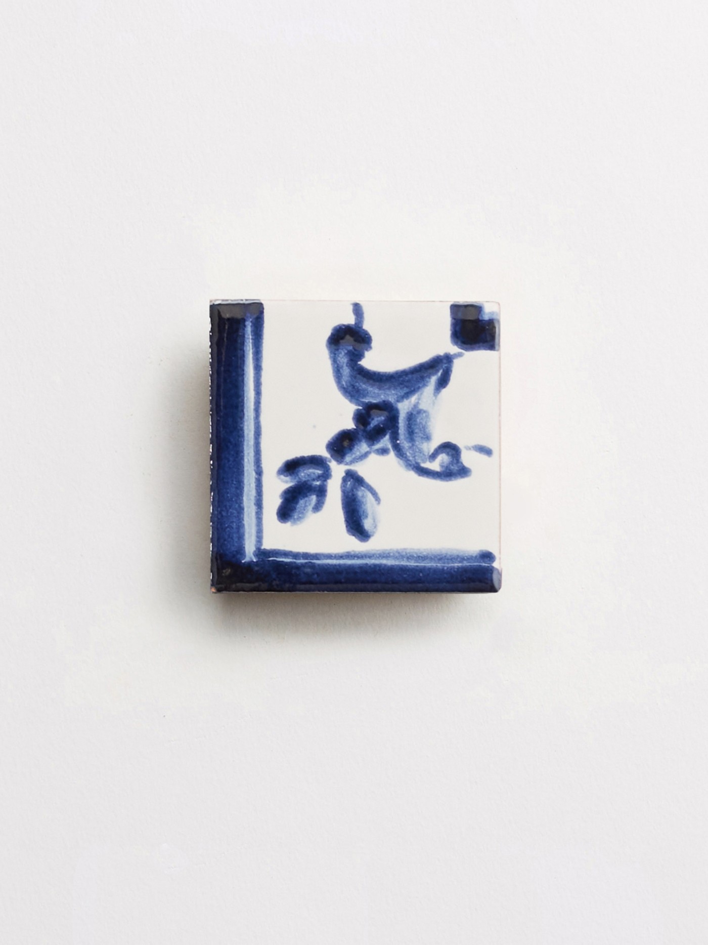 a blue and white tile with a floral design on a white surface.