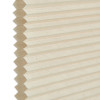 Honeycomb cellular blind, beige pleated fabric with visible hexagonal cell edges at left; closed and flat. Close-up against a neutral white background with soft, diffused indoor lighting.