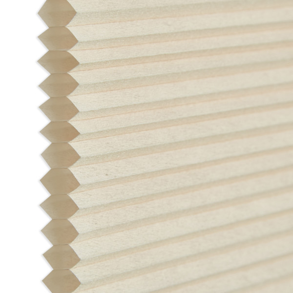 Honeycomb cellular blind, beige pleated fabric with visible hexagonal cell edges at left; closed and flat. Close-up against a neutral white background with soft, diffused indoor lighting.