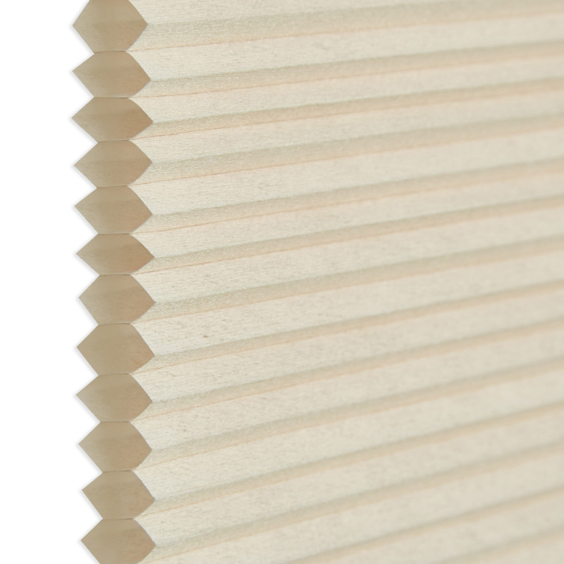 Honeycomb cellular blind, beige pleated fabric with visible hexagonal cell edges at left; closed and flat. Close-up against a neutral white background with soft, diffused indoor lighting.