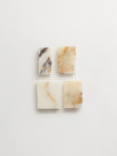 four squares of soap on a white surface.
