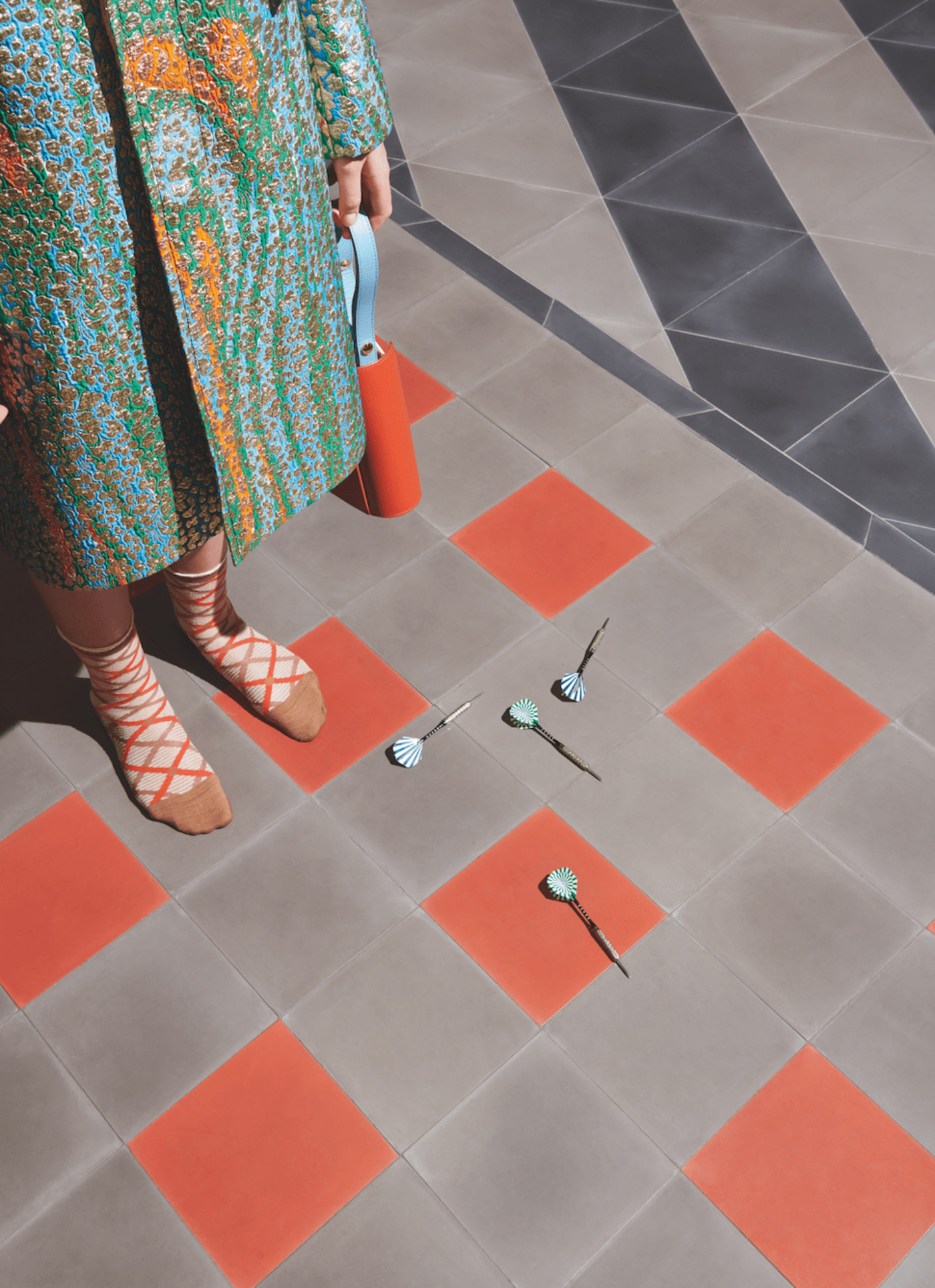 a woman in a colorful coat standing on a tiled floor.