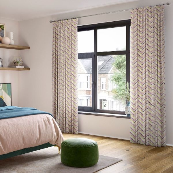 Patterned pleated curtains on a silver rod, full‑length panels with pastel chevron, pulled to frame a black‑framed window and filtering daylight in a bedroom with view of brick houses.