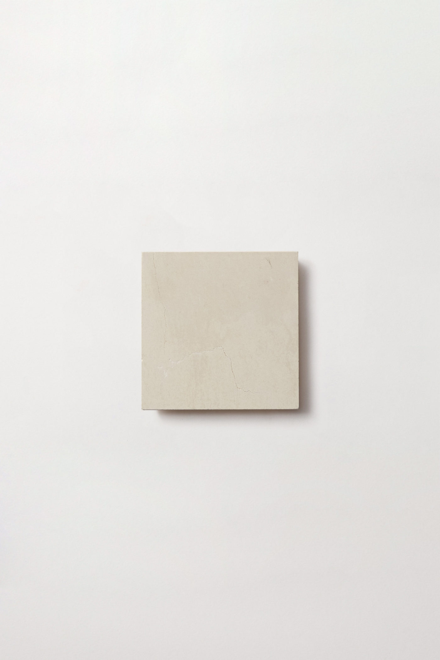 An off white square tile centered on a white background.