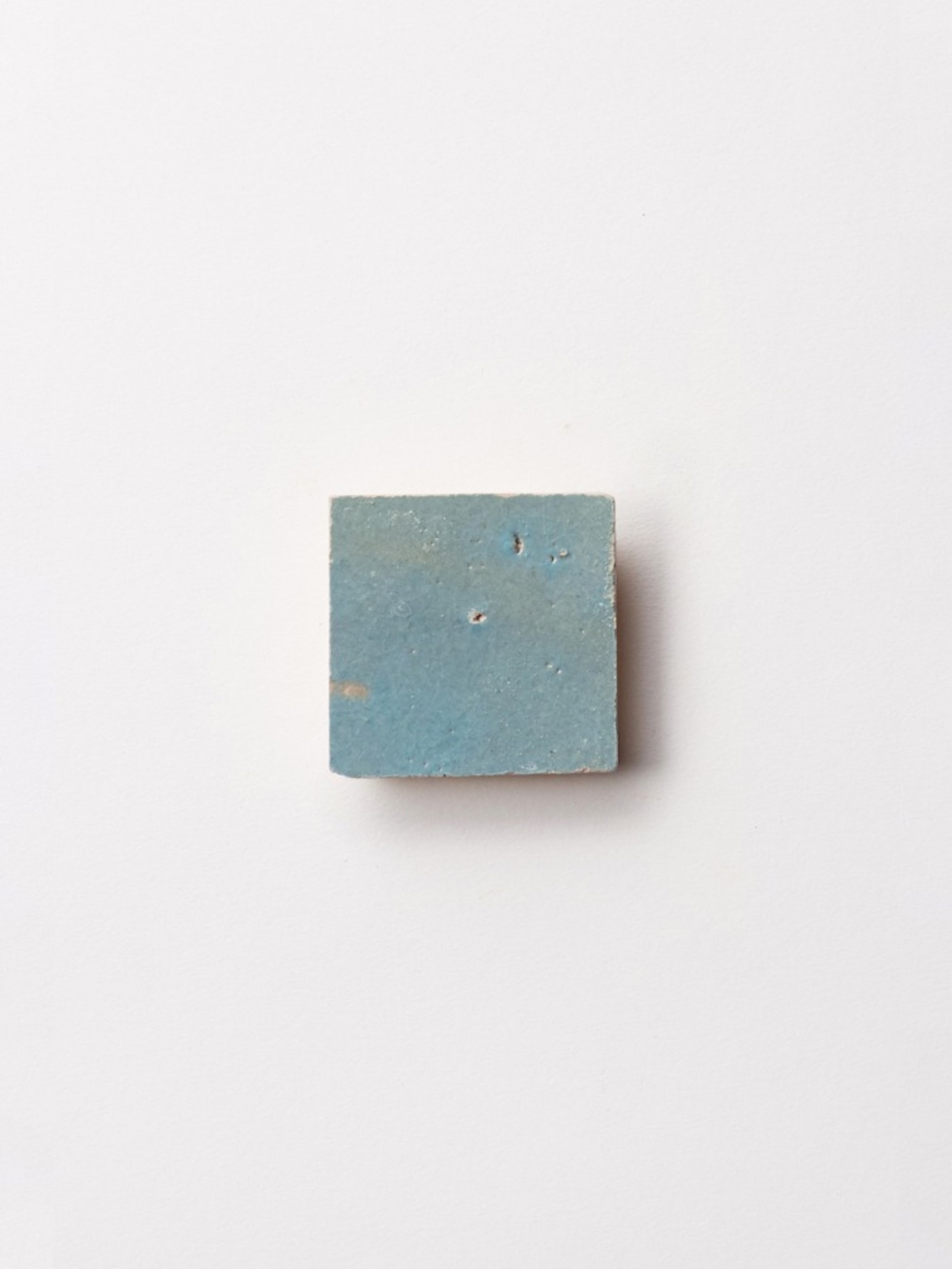 a square blue tile on a white surface.