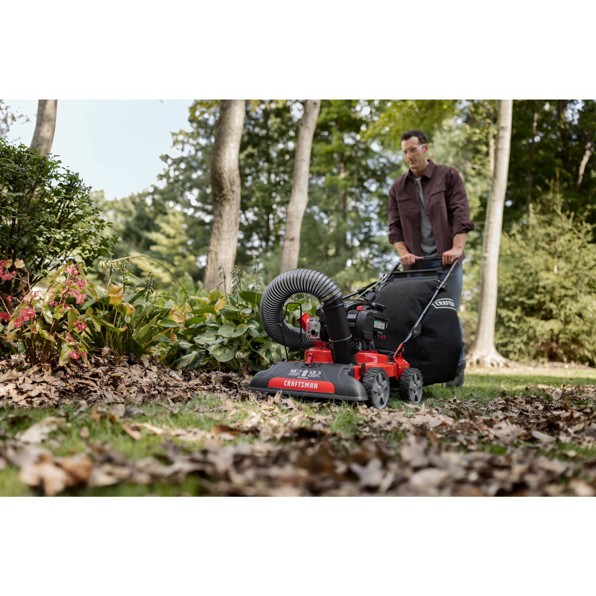 CRAFTSMAN 24-In. 163cc Chipper Shredder Vacuum attached to mower mowing up leaves in wooded area