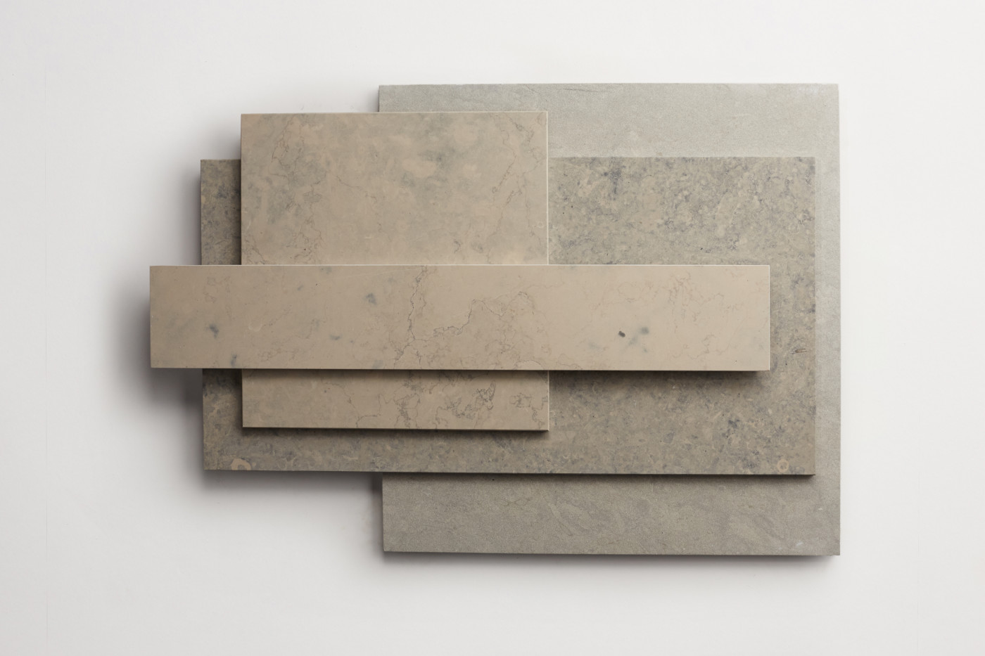 a stack of various sized limestone tiles on a white surface.