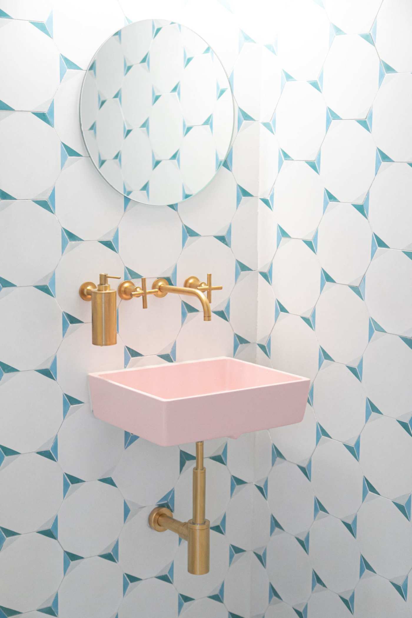 a bathroom with a pink sink and blue and white tiled walls.