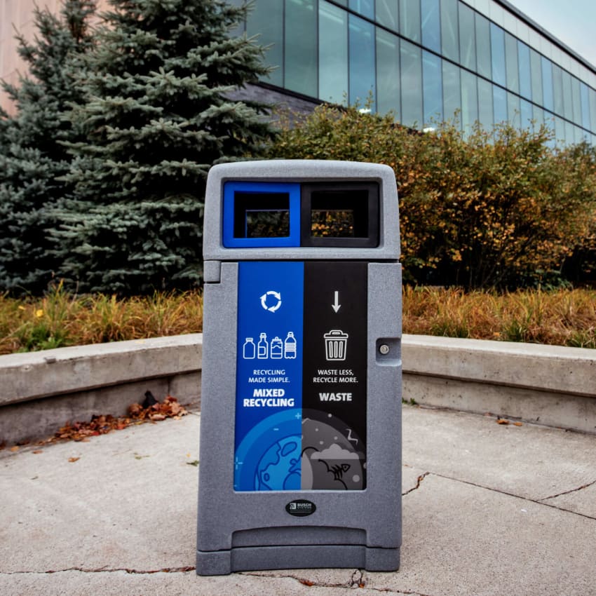 double mixed recycling and waste bin with outdoor canopy lid and colored openings outside at a recreation facility