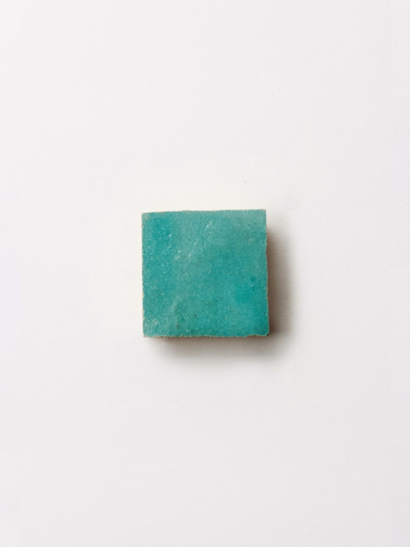 a square piece of turquoise tile on a white background.