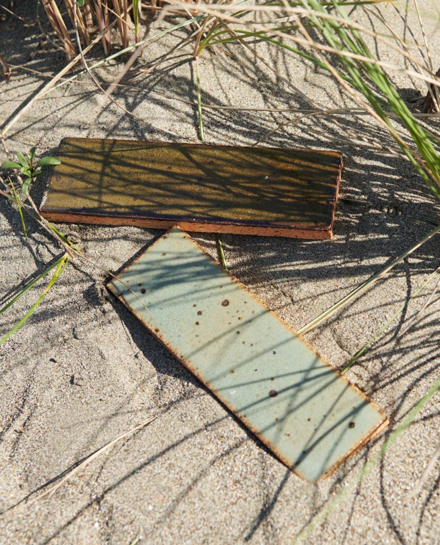 two rectangle tiles laying in the sand.