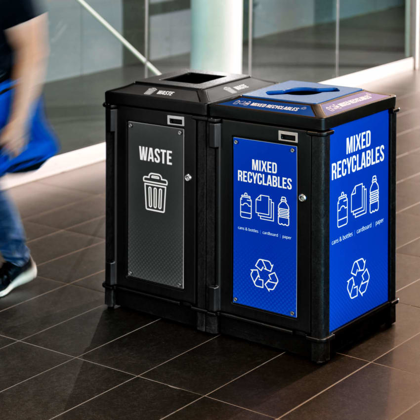 black recycled plastic waste and recycling container with bold signs and labels inside a fitness center