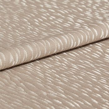 Beige jacquard fabric with glossy, raised crescent pattern; folded once across the frame, overlapping edges; close-up studio view with soft, diffuse lighting emphasizing the textured sheen.