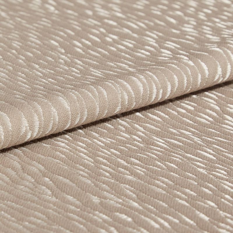 Beige jacquard fabric with glossy, raised crescent pattern; folded once across the frame, overlapping edges; close-up studio view with soft, diffuse lighting emphasizing the textured sheen.