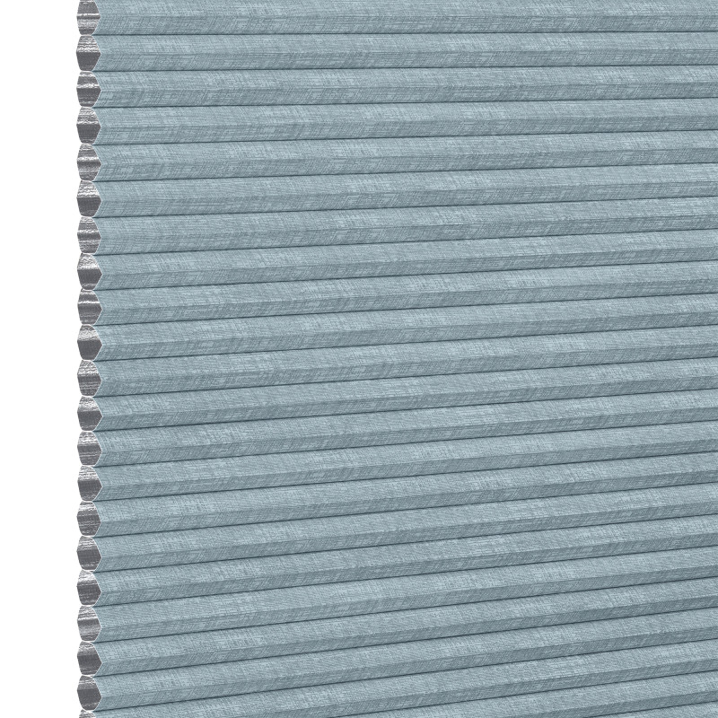 Light-blue textured cellular (honeycomb) pleated shade, tightly closed showing hexagonal cell edges at left; blocking light and insulating a window within a softly lit interior, neutral background.