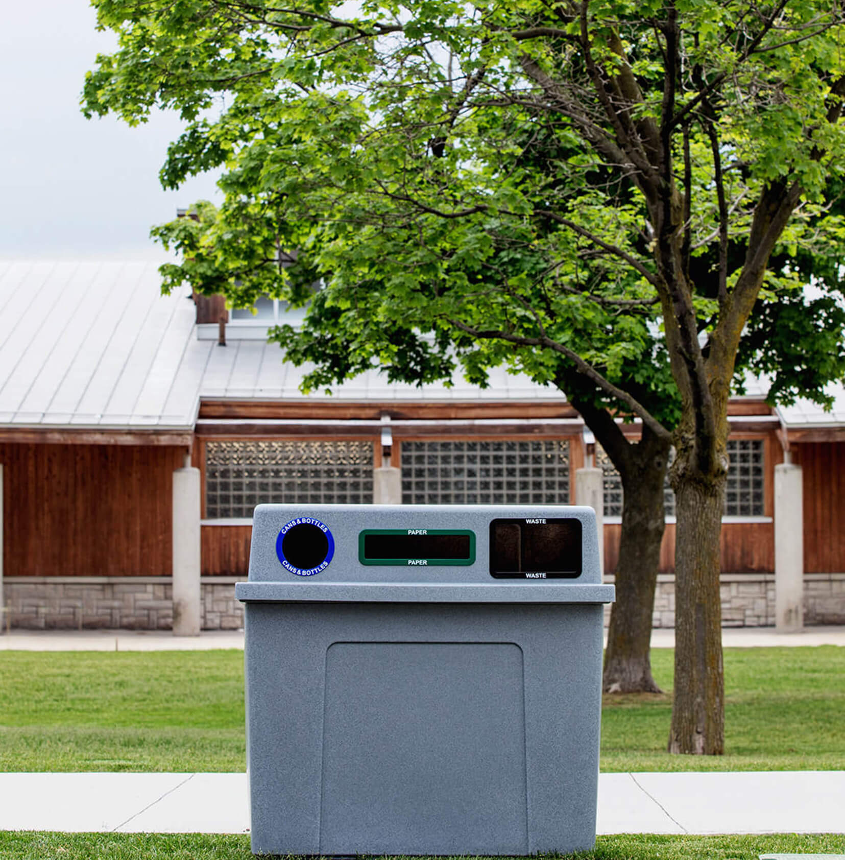 triple stream recycling and waste station with grey plastic body and color coded openings at a city park