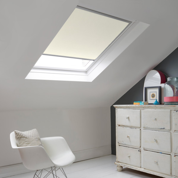 Room with white eaves wall, dark blue-grey wall to right with a shabby chic white drawer unit, a contemporary white chair, white painted floorboards and a skylight blind in natural.
