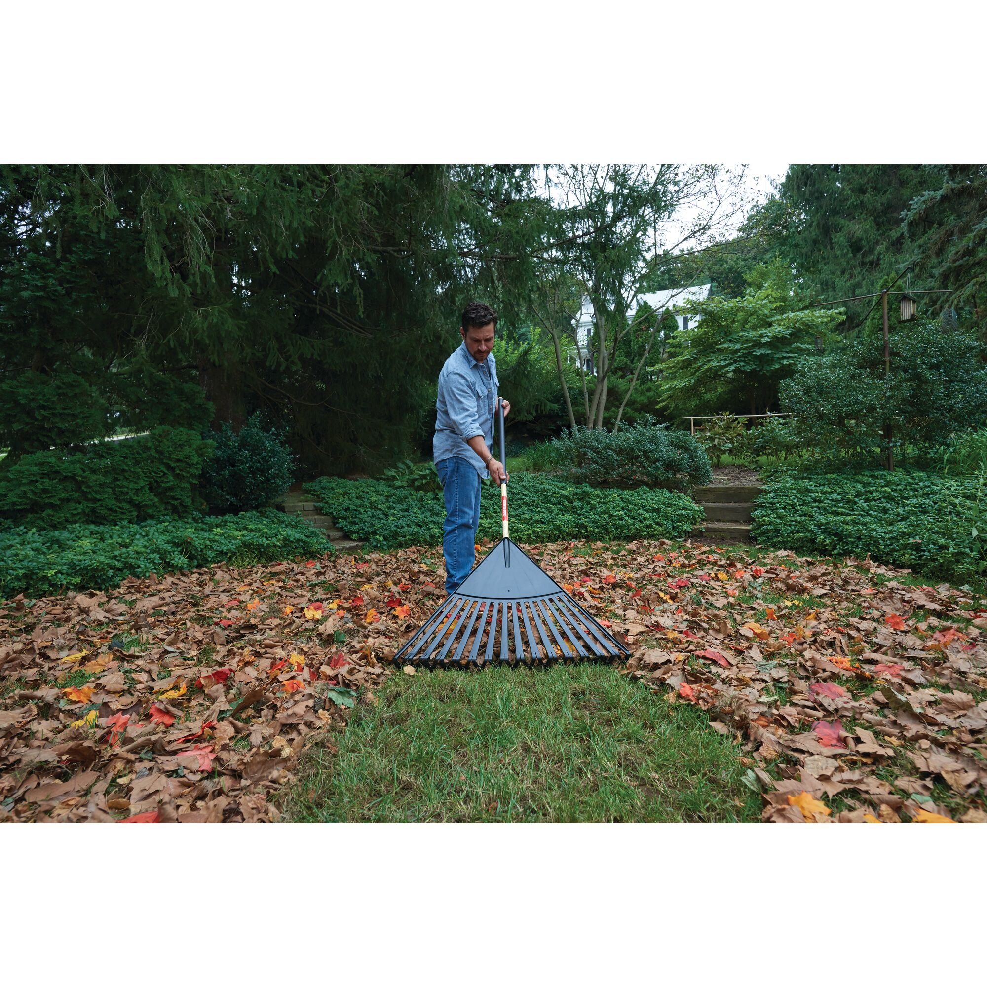 Wood handle 30 inch leaf rake being used by a person.