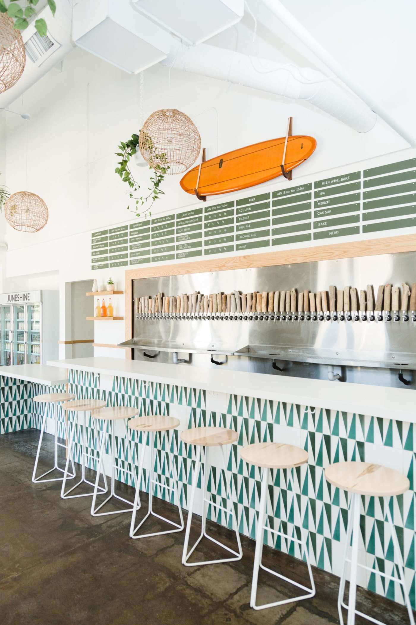 a bar with stools and a surfboard hanging on the wall.