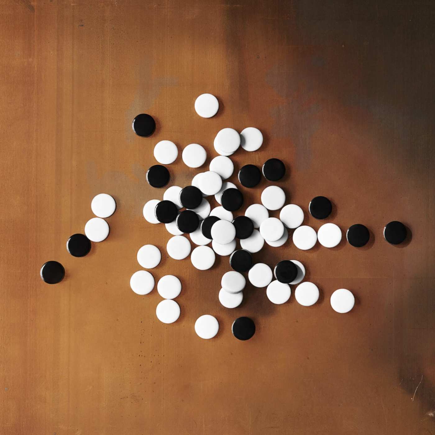 a pile of black and white ceramic tiles on a brown surface.