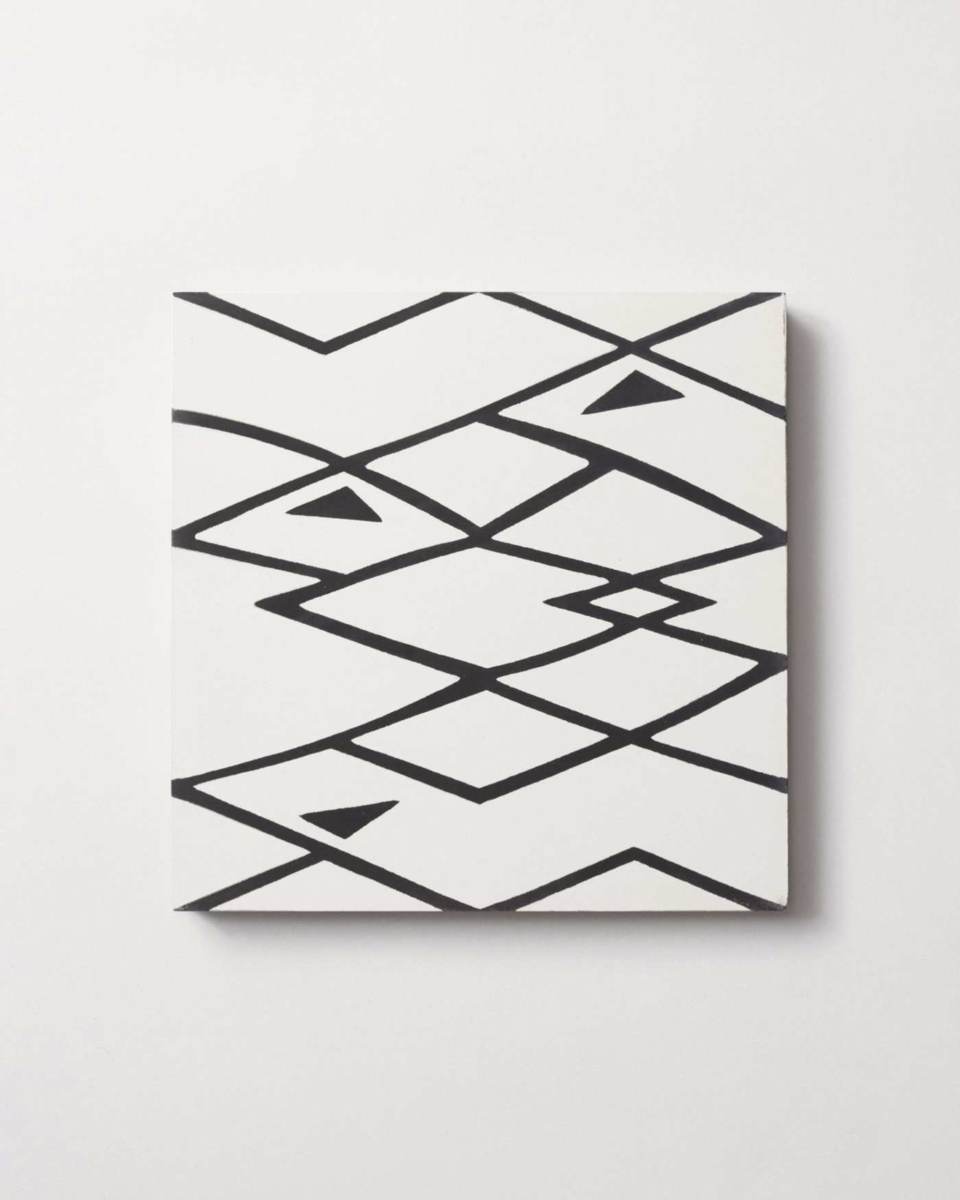 a black and white tile with an abstract pattern on a white surface.