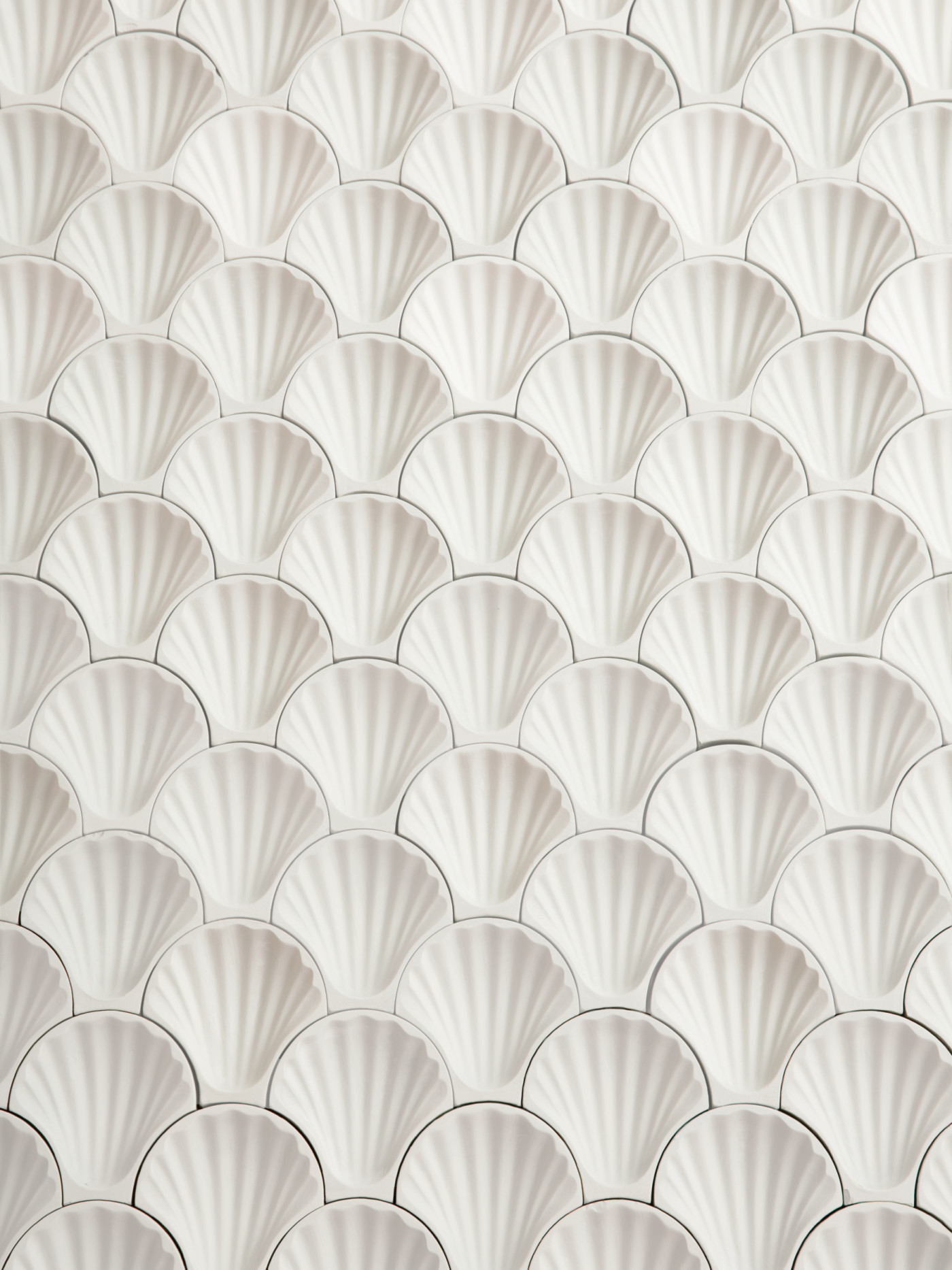 a surface of white tiles in the shape of shells.