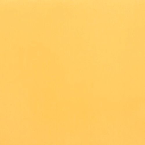 Ochre sheet of paper fills the frame (object), lying flat (action); soft, even lighting reveals slight texture in a uniform close-up field (context).