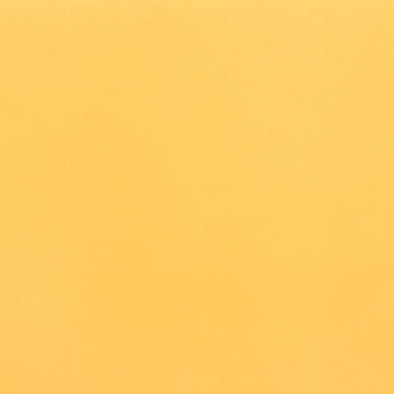 Ochre sheet of paper fills the frame (object), lying flat (action); soft, even lighting reveals slight texture in a uniform close-up field (context).