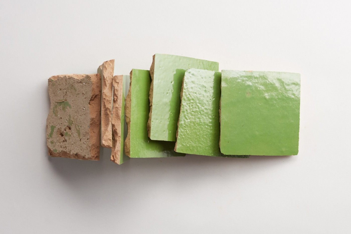 a stack of green tiles on a white surface.